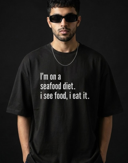 Man wearing a black t-shirt with a humorous text design on a dark background